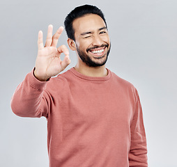 Image showing Perfect, winking and portrait of an Asian man with a hand gesture isolated on a white background in studio. Ok, review and a flirty guy with a wink and emoji sign for satisfaction and happiness