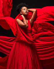 Image showing Beauty, black woman and art in fashion, fabric on dark background and motion in aesthetic movement. Flowing silk, fantasy and artistic, sensual African model in red creative designer dress in studio.