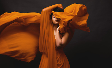 Image showing Black woman, art and fashion, fabric movement on dark background with beauty and aesthetic motion. Flowing silk, fantasy and artistic, serious African model in brown creative designer dress in studio