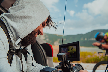 Image showing A cameraman with professional equipment and camera stabilization films a triathlete on the move riding a bicycle