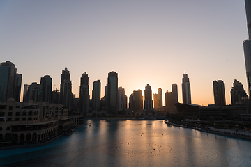 Image showing Dubai singing fountains at night lake view between skyscrapers. City skyline in dusk modern architecture in UAE capital downtown.