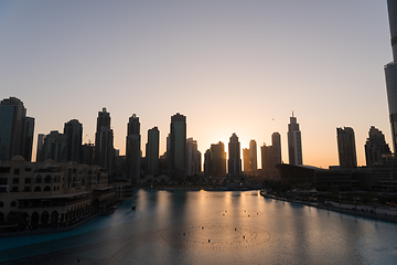 Image showing Dubai singing fountains at night lake view between skyscrapers. City skyline in dusk modern architecture in UAE capital downtown.