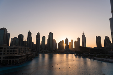 Image showing Dubai singing fountains at night lake view between skyscrapers. City skyline in dusk modern architecture in UAE capital downtown.