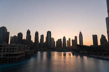 Image showing Dubai singing fountains at night lake view between skyscrapers. City skyline in dusk modern architecture in UAE capital downtown.