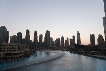 Image showing Dubai singing fountains at night lake view between skyscrapers. City skyline in dusk modern architecture in UAE capital downtown.