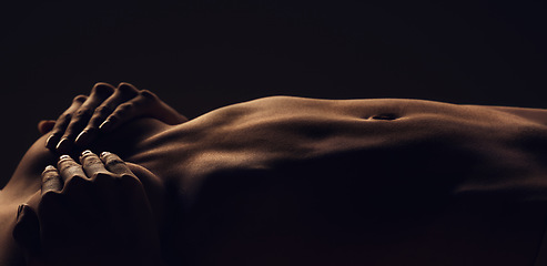 Image showing Stomach, woman and breast silhouette dark background of skin, body and model with glow, light and art on black. Hands of aesthetic person in studio for abstract, creativity and shadow or space