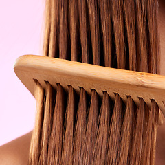 Image showing Beauty, comb and wood with hair of woman for health, salon and close up in studio. Wellness, keratin and natural bamboo brush with female model for cosmetics, self care and shine on pink background