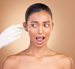 Image showing Woman, needle and face in studio with fear of pain with cosmetics, surgery and brown background. Young, model and syringe for facial cosmetic and collagen filler for skincare, dermatology and change