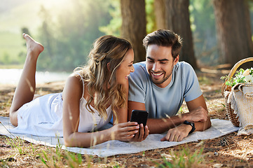 Image showing Couple on picnic with smartphone, relax together in nature and social media with travel and bonding outdoor. Happiness, man and woman lying down and scroll internet in forest with smile