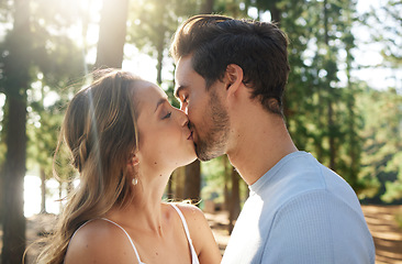 Image showing Couple kiss in forest, love and summer with freedom and adventure, affection in relationship and care outdoor. People together in nature park, commitment and trust with romance, content and sunshine