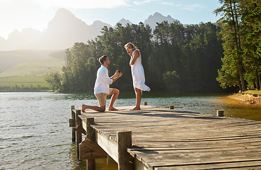 Image showing Man, woman and engagement proposal by lake on vacation with surprise, wow or happiness in sunshine. Couple, marriage offer and ring in nature for romance, love and happy on holiday in summer by water