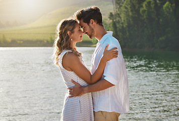 Image showing Couple, head touch and hug by lake for outdoor date, romantic adventure and summer love in nature. Man, woman and romance with embrace, care and bond by water with sunshine, freedom and happiness