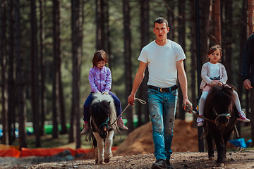 Image showing Two little girls having fun in the park while riding small horses