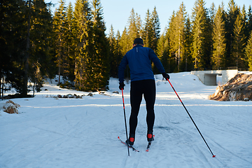 Image showing Nordic skiing or Cross-country skiing classic technique practiced by man in a beautiful panoramic trail at morning.Selective focus.