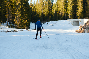 Image showing Nordic skiing or Cross-country skiing classic technique practiced by man in a beautiful panoramic trail at morning.Selective focus.