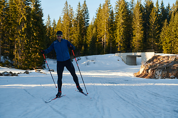 Image showing Nordic skiing or Cross-country skiing classic technique practiced by man in a beautiful panoramic trail at morning.Selective focus.