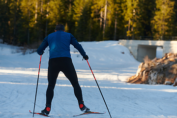 Image showing Nordic skiing or Cross-country skiing classic technique practiced by man in a beautiful panoramic trail at morning.Selective focus.