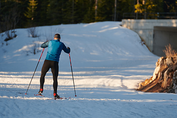 Image showing Nordic skiing or Cross-country skiing classic technique practiced by man in a beautiful panoramic trail at morning.Selective focus.