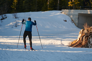 Image showing Nordic skiing or Cross-country skiing classic technique practiced by man in a beautiful panoramic trail at morning.Selective focus.