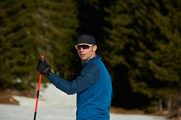 Image showing Nordic skiing or Cross-country skiing classic technique practiced by man in a beautiful panoramic trail at morning.Selective focus.