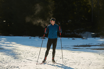 Image showing Nordic skiing or Cross-country skiing classic technique practiced by man in a beautiful panoramic trail at morning.Selective focus.