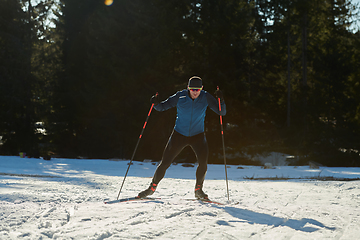 Image showing Nordic skiing or Cross-country skiing classic technique practiced by man in a beautiful panoramic trail at morning.Selective focus.