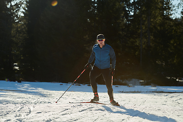 Image showing Nordic skiing or Cross-country skiing classic technique practiced by man in a beautiful panoramic trail at morning.Selective focus.