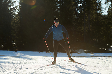 Image showing Nordic skiing or Cross-country skiing classic technique practiced by man in a beautiful panoramic trail at morning.Selective focus.