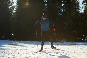 Image showing Nordic skiing or Cross-country skiing classic technique practiced by man in a beautiful panoramic trail at morning.Selective focus.