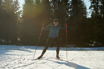 Image showing Nordic skiing or Cross-country skiing classic technique practiced by man in a beautiful panoramic trail at morning.Selective focus.