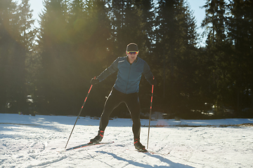 Image showing Nordic skiing or Cross-country skiing classic technique practiced by man in a beautiful panoramic trail at morning.Selective focus.