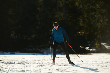 Image showing Nordic skiing or Cross-country skiing classic technique practiced by man in a beautiful panoramic trail at morning.Selective focus.