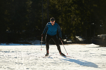 Image showing Nordic skiing or Cross-country skiing classic technique practiced by man in a beautiful panoramic trail at morning.Selective focus.