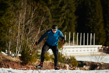 Image showing Nordic skiing or Cross-country skiing classic technique practiced by man in a beautiful panoramic trail at morning.Selective focus.