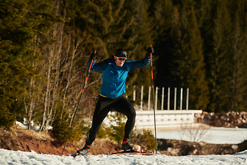 Image showing Nordic skiing or Cross-country skiing classic technique practiced by man in a beautiful panoramic trail at morning.Selective focus.