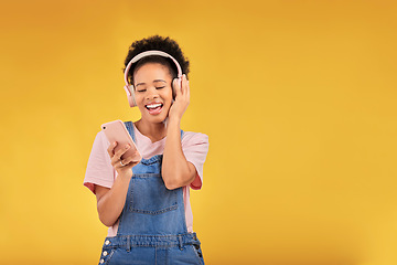 Image showing Music, headphones and happy black woman with phone in studio isolated on a yellow background mockup space. Person, excited and listen to radio, podcast or sound for jazz, hip hop or streaming audio