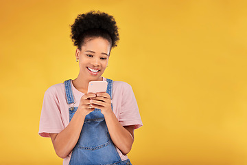 Image showing Smile, typing and woman with phone in studio, texting or social media post with mockup on yellow background. Networking, chat online and happy model with cellphone mobile app, reading meme or email