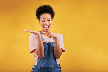 Image showing Branding, advertising and a black woman pointing to her palm for the promotion of a product on a yellow background in studio. Smile, marketing or space with a happy young female brand ambassador