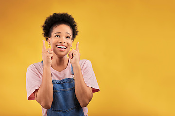 Image showing Smile, pointing and mockup with a black woman on a yellow background in studio for advertising or marketing. Sale, presentation or information with a happy young female brand ambassador showing space