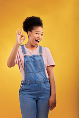 Image showing Portrait, okay and hand gesture with an excited black woman in studio on a yellow background. Smile, wow and perfect with a happy young female person showing a sign of support, feedback or review