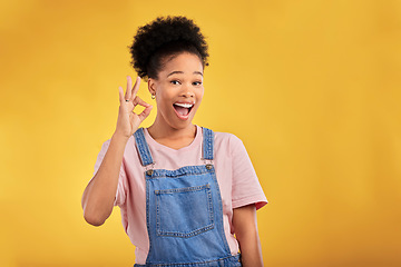 Image showing Portrait, okay and hand gesture with a happy black woman in studio on a yellow background. Smile, wow and perfect with an excited young female person showing a sign of support, feedback or review
