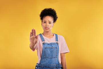 Image showing Stop, hand and warning with portrait of black woman in studio for emoji, no and voice. Rejection, opinion and sign with person on yellow background for protest, discrimination and forbidden icon