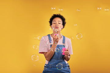 Image showing Woman, blowing bubbles and fun in studio while playful for birthday, happiness or party celebration. Black female model person with liquid soap, natural beauty and fashion on a yellow background