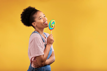 Image showing Black woman, portrait and eating candy or lollipop in studio on yellow background and sweets, dessert or food with sugar. Gen z, girl and guilty pleasure in delicious treats, snack or product