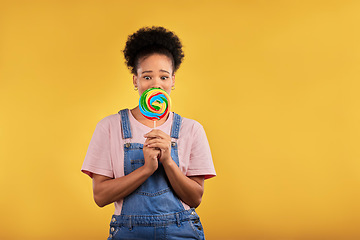 Image showing Black woman, portrait with candy or lollipop in studio on yellow background and eating sweets, dessert or food with sugar. Gen z, girl and guilty pleasure in delicious treats, snack or product