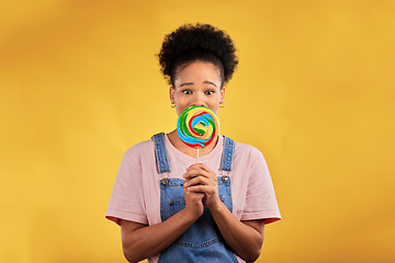 Image showing Portrait, black woman with candy or lollipop in studio on yellow background and eating sweets, dessert or food with sugar. Gen z, face of girl and hungry for delicious treats, snack or product