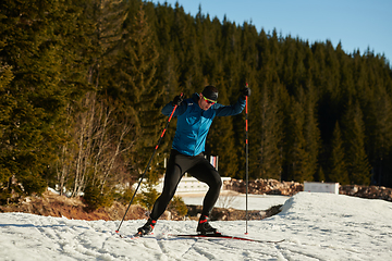 Image showing Nordic skiing or Cross-country skiing classic technique practiced by man in a beautiful panoramic trail at morning.Selective focus.