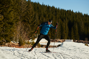 Image showing Nordic skiing or Cross-country skiing classic technique practiced by man in a beautiful panoramic trail at morning.Selective focus.