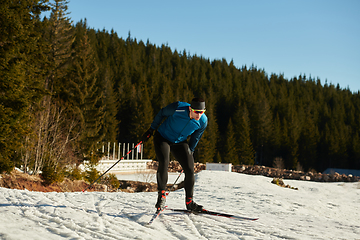 Image showing Nordic skiing or Cross-country skiing classic technique practiced by man in a beautiful panoramic trail at morning.Selective focus.