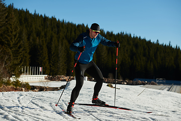 Image showing Nordic skiing or Cross-country skiing classic technique practiced by man in a beautiful panoramic trail at morning.Selective focus.